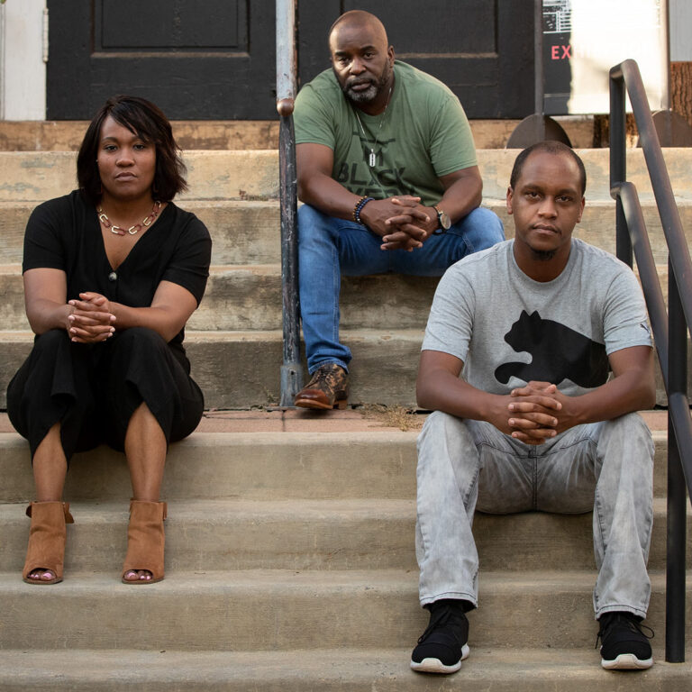 Three black team members of In My Humble Opinion Radio Show sitting on steps in Charlottesville VA