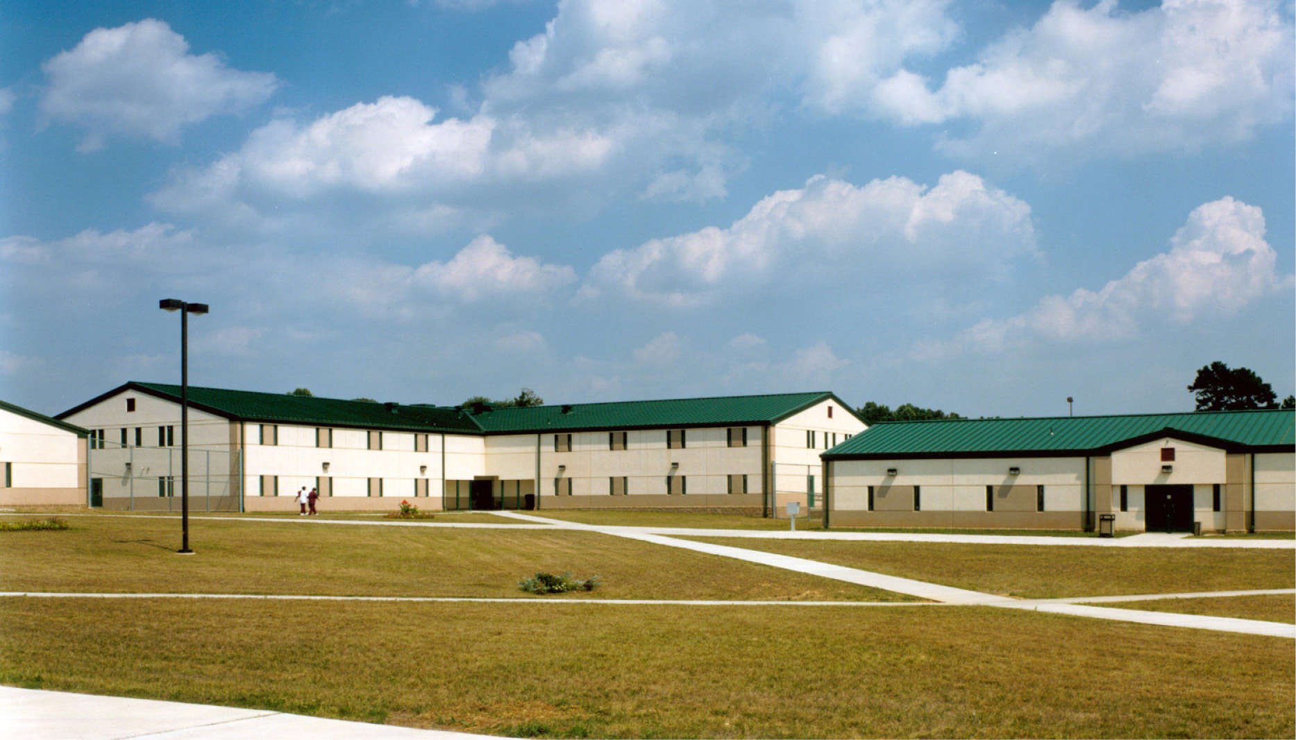 A one-story complex with green roofs, pictured with a blue sky and puffy clouds.