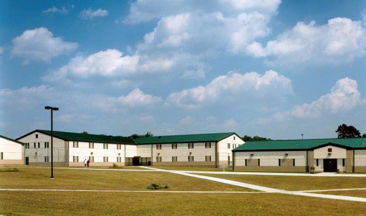 A one-story complex with green roofs, pictured with a blue sky and puffy clouds.